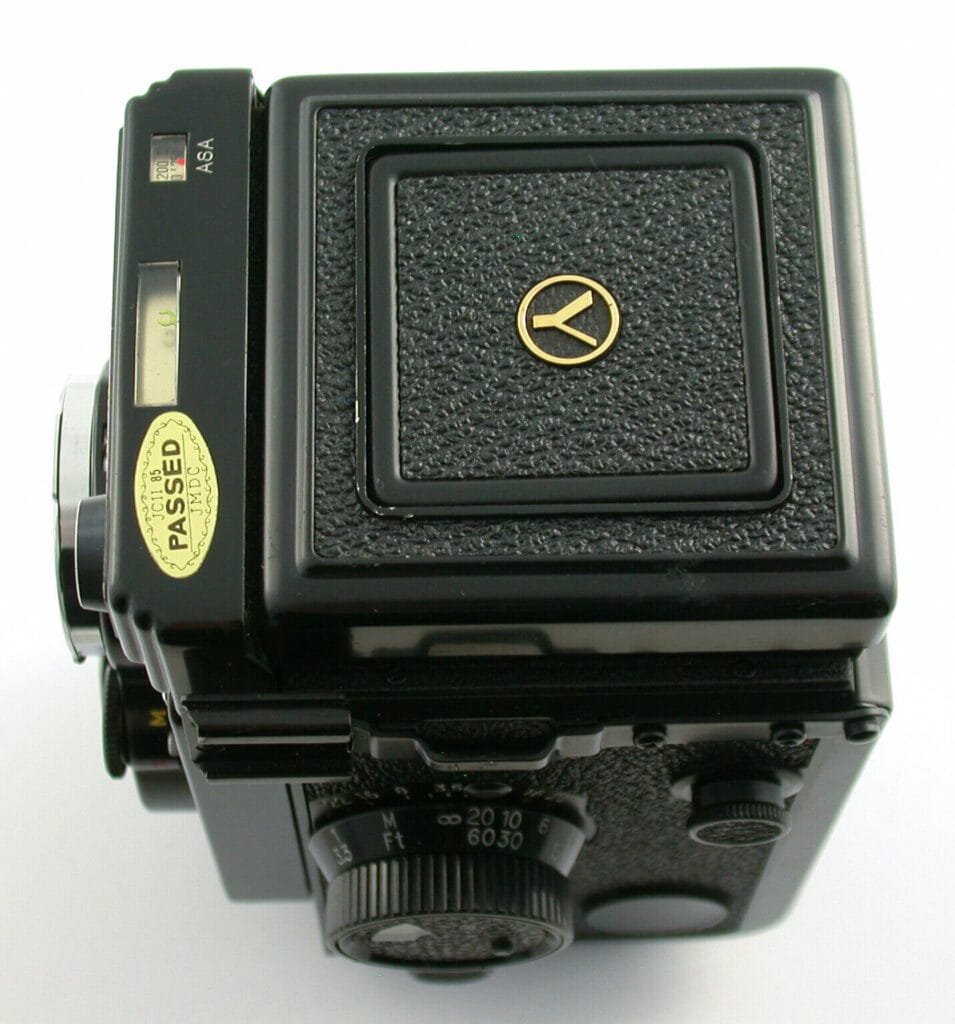 Vue de dessus du Yashica Mat-124G, avec le logo doré sur le capot supérieur et la molette de mise au point visible.