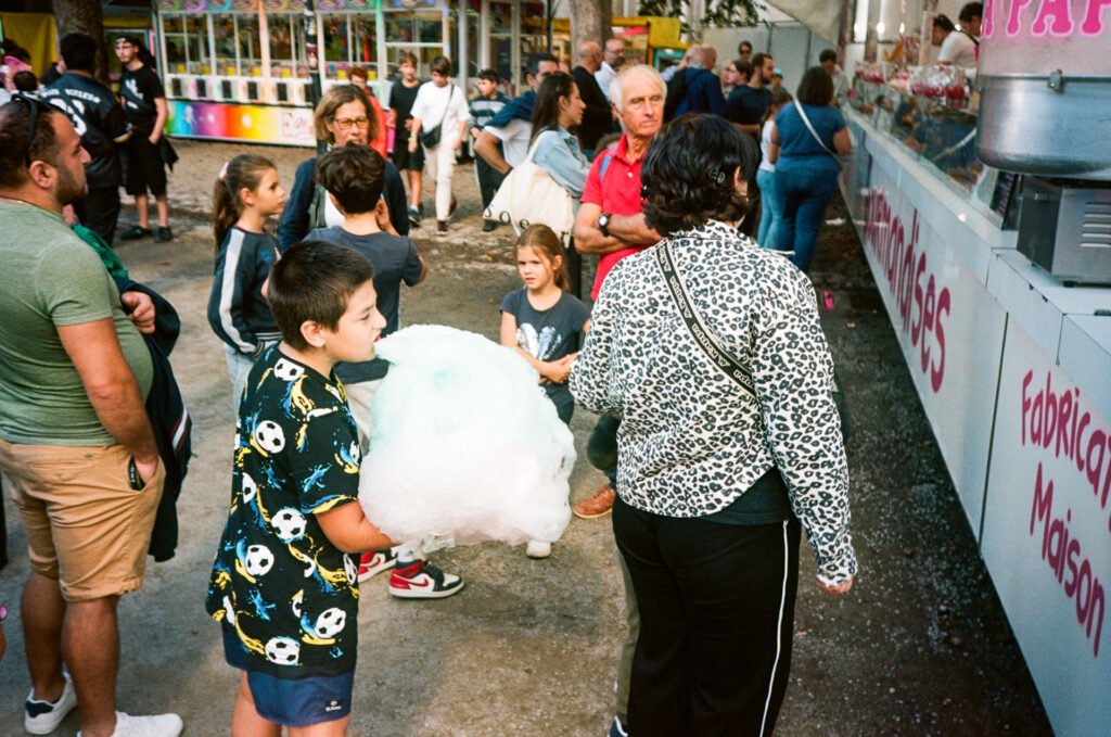 Un enfant mange une énorme barbe à papa devant un stand de confiseries lors de la fête foraine de Nantes.