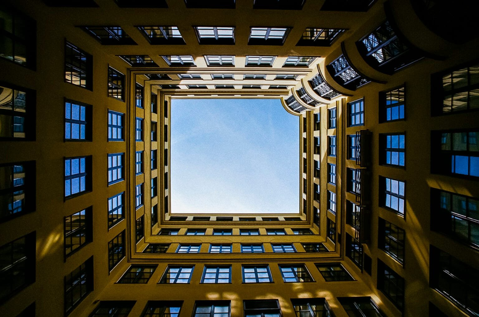 Vue en contre-plongée d’une cour intérieure à Munich, encadrant un ciel bleu, prise au grand-angle.