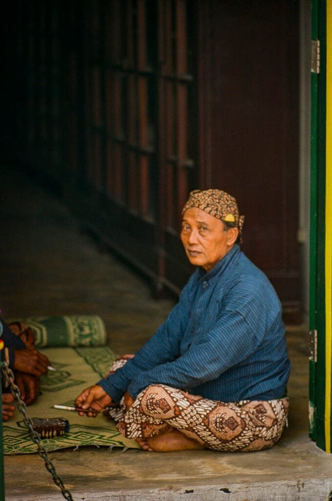 Portrait d’un garde javanais en tenue traditionnelle, assis en tailleur dans le palais du Kraton à Yogyakarta.