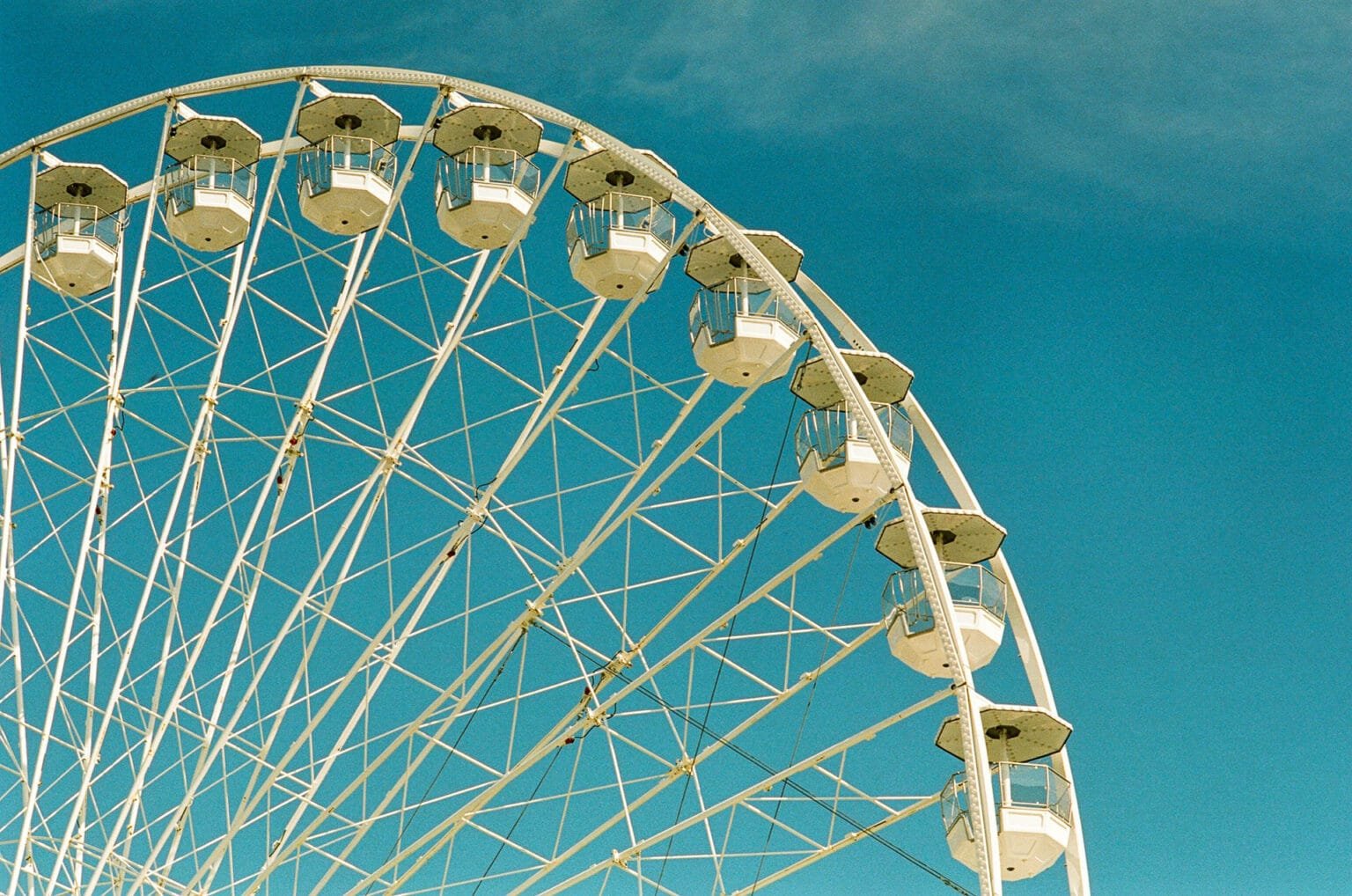 Vue partielle de la grande roue de Nantes sur fond de ciel bleu, capturée avec un téléobjectif en photographie argentique.