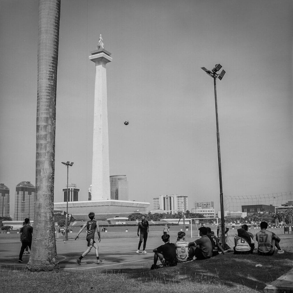 Jeunes jouant au football devant le Monumen Nasional à Jakarta, sur la place Lapangan Merdeka.