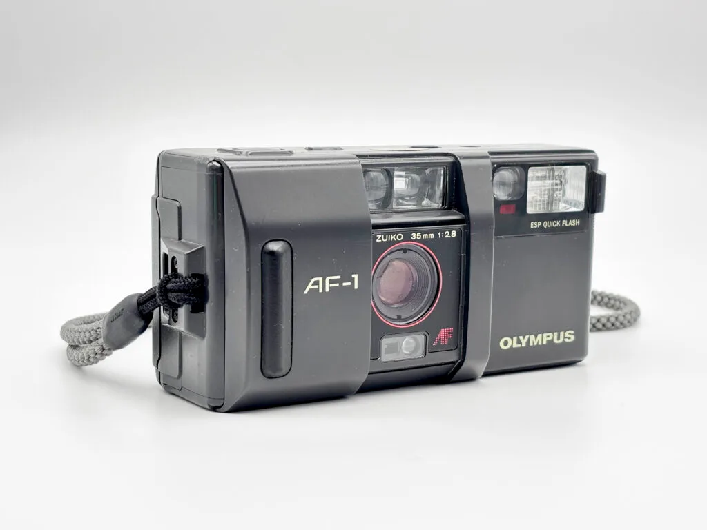 Olympus AF-1 avec le capot ouvert laissant apparaître l’objectif Zuiko 35 mm f/2.8.