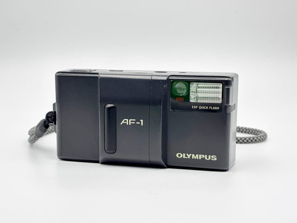 Vue frontale de l’Olympus AF-1, compact argentique autofocus avec flash intégré.