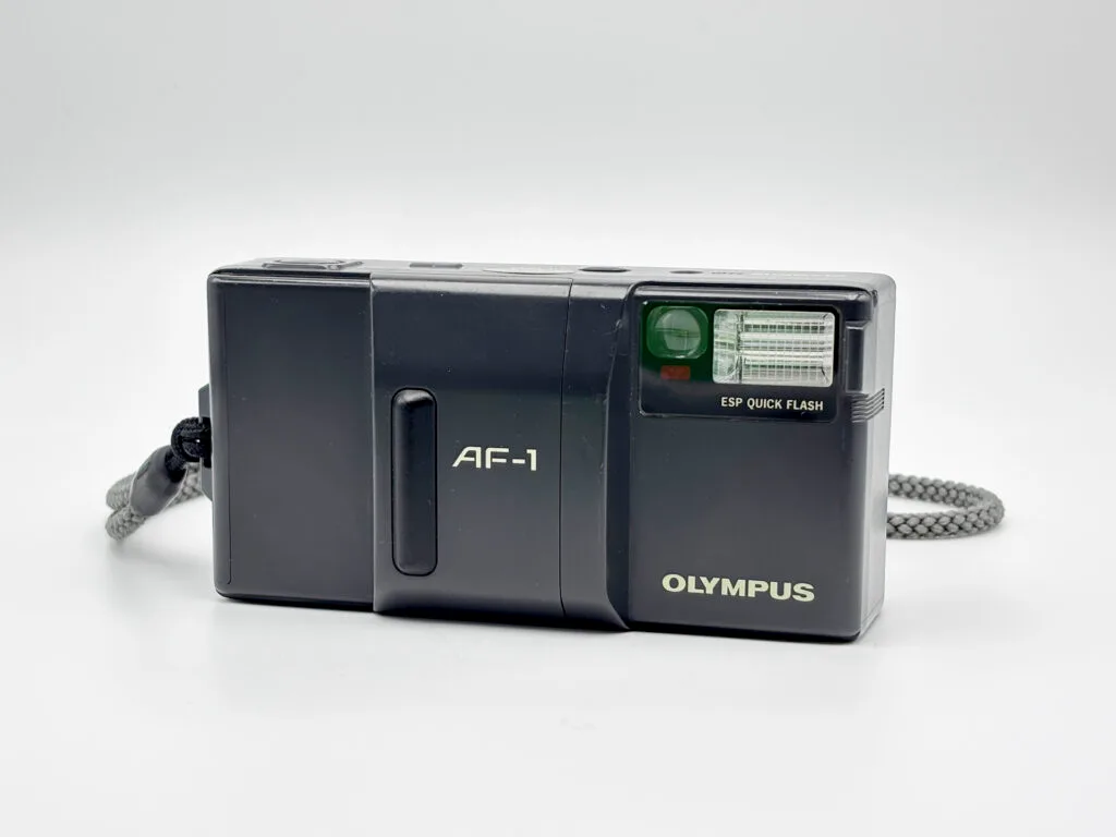 Vue frontale de l’Olympus AF-1, compact argentique autofocus avec flash intégré.