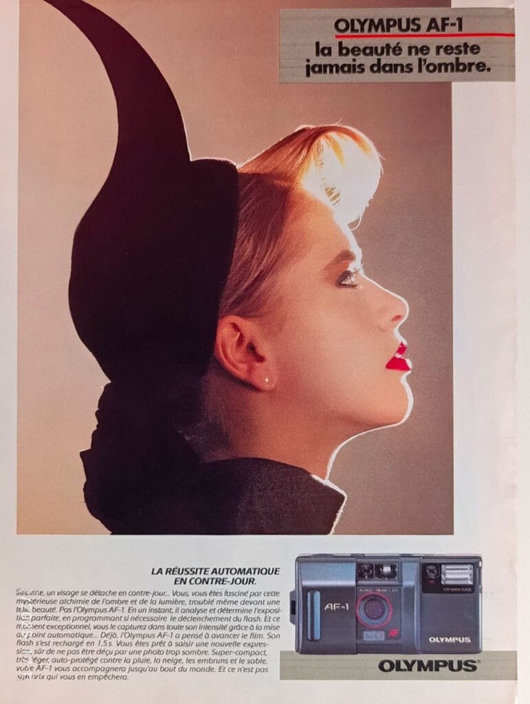 Publicité des années 80 pour l’Olympus AF-1 avec le slogan “La beauté ne reste jamais dans l’ombre”.