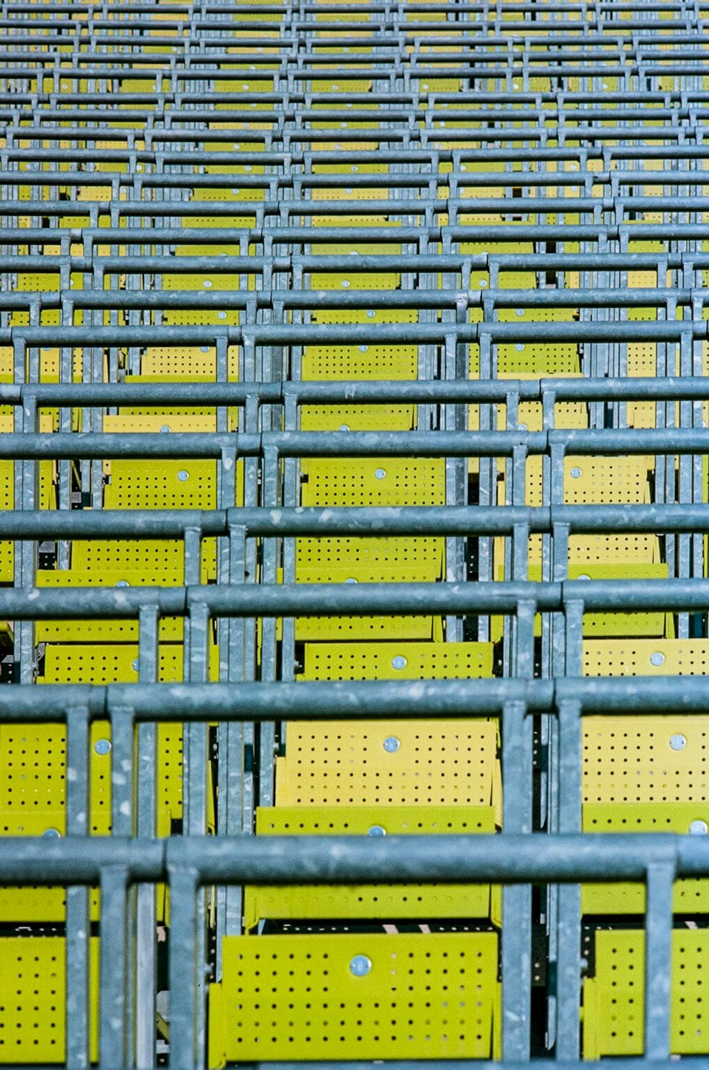 Répétition de structures métalliques et de sièges verts perforés dans les gradins du Stade Olympique de Munich.