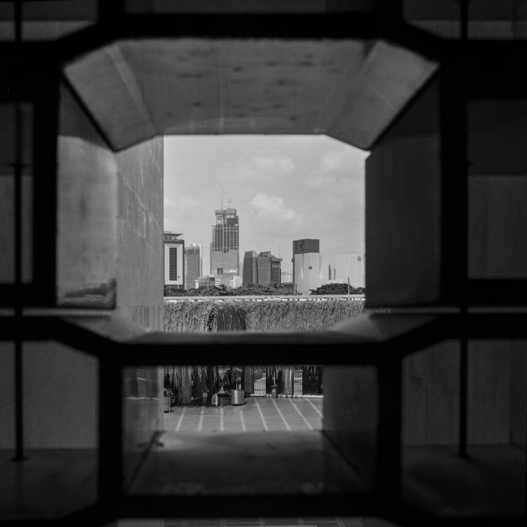 Vue de Jakarta encadrée par une ouverture en béton depuis l’intérieur de la mosquée Istiqlal.