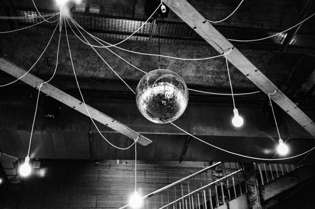 Boule à facettes suspendue au plafond du bar du Lieu Unique à Nantes, entourée d’ampoules nues et de câbles apparents.
