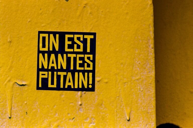 Sticker collé sur la structure métallique jaune de la Grue Titan à Nantes, photographié en Kodak Gold 200 avec un Nikon F3 HP.