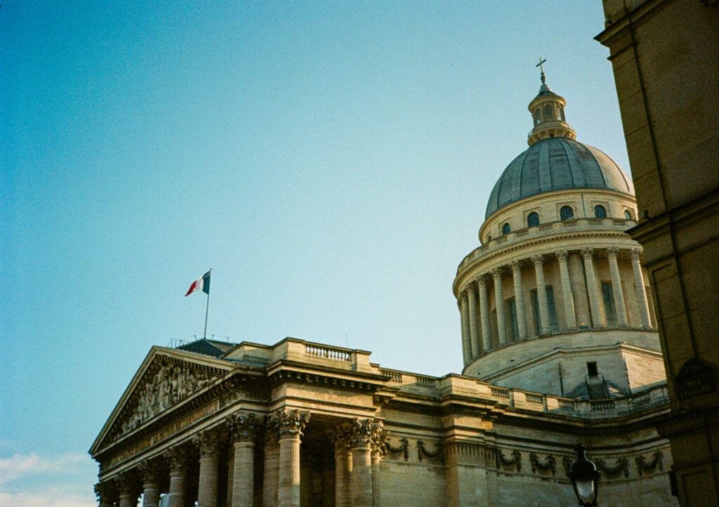 Façade du Panthéon et son dôme à Paris, sous un ciel clair. Drapeau français en berne quelques jours après l’hommage à Robert Badinter. Photo prise avec un Canon Dial 35-2 sur pellicule Portra 160.