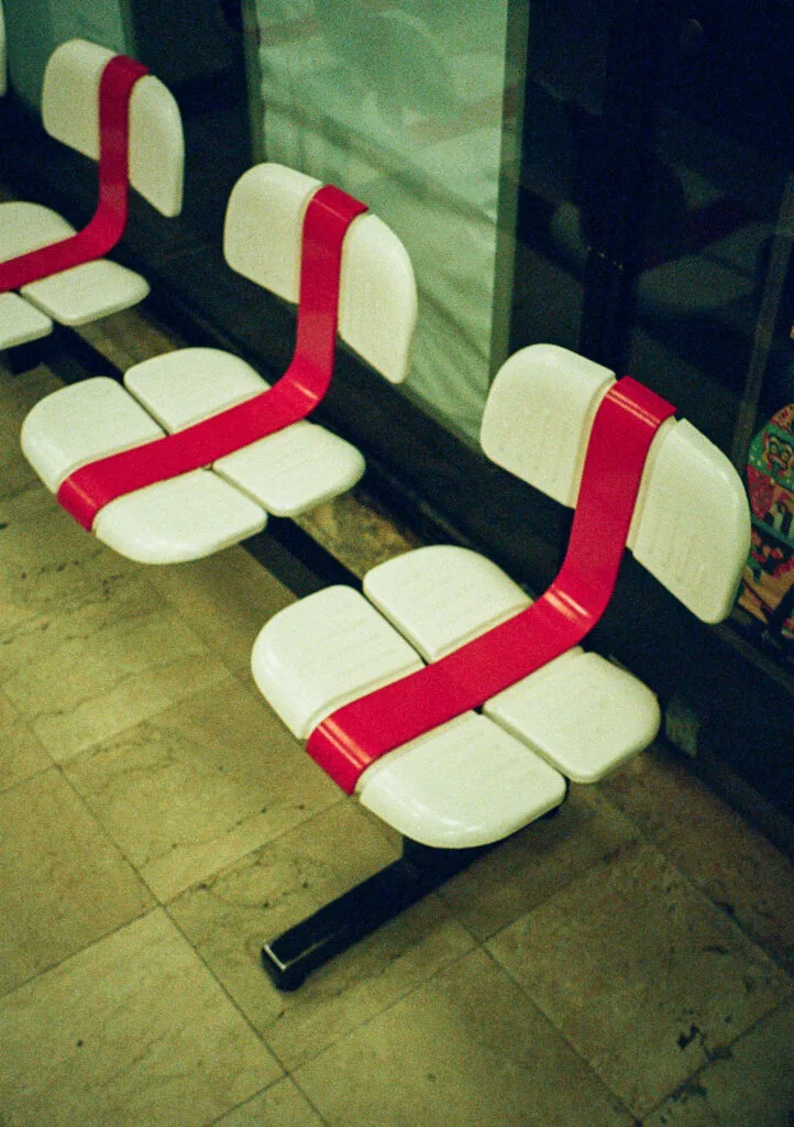 Chaises blanches barrées de ruban rouge dans une laverie de nuit à Paris, prises en photo en argentique.