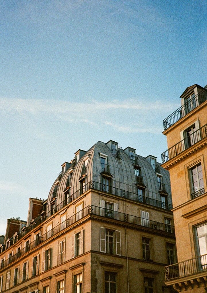 Immeuble haussmannien avec toiture en zinc photographié à contre-jour depuis la rue de Rivoli, en lumière dorée.