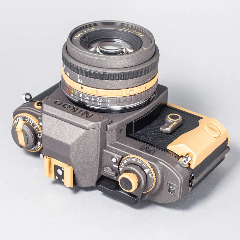 Nikon FG revisité par Eye Out Camera, finition bicolore bronze et or, objectif 50 mm f/1.8 monté.