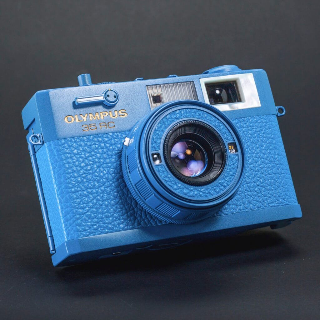 Olympus 35 RC revisité par Eye Out Camera, finition bleue mate avec incrustations de nacre, boîtier compact télémétrique des années 70.