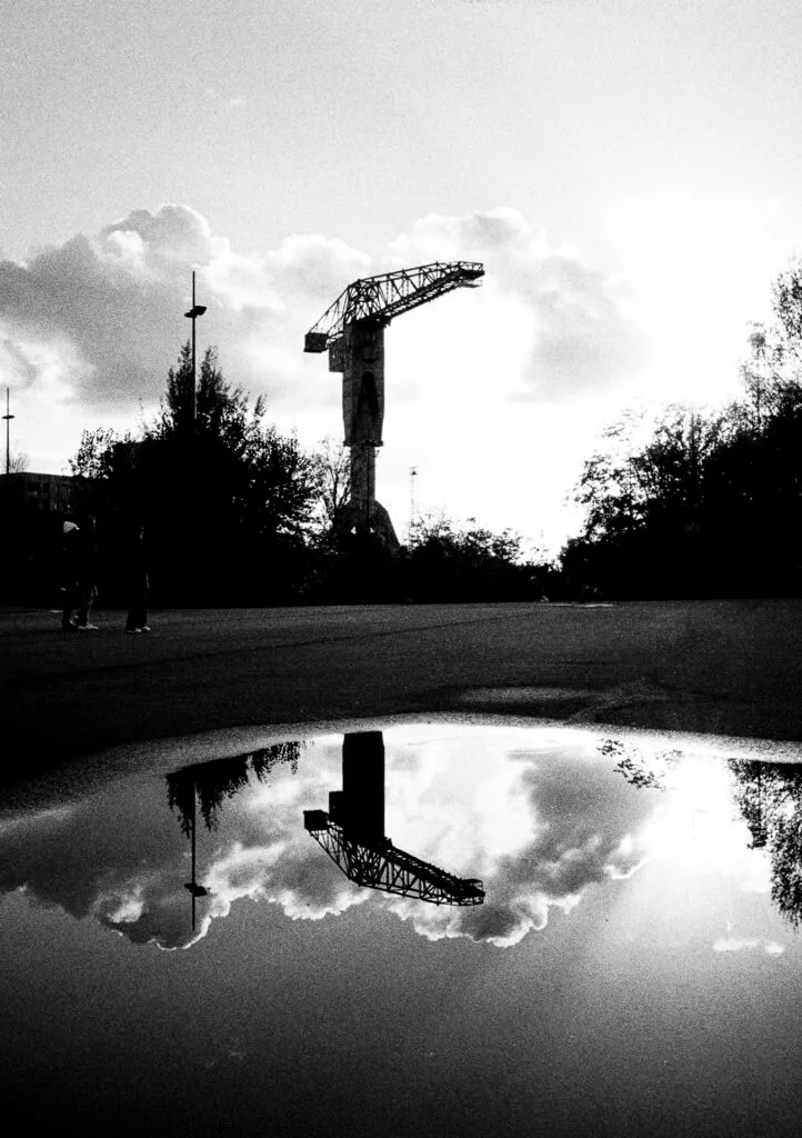 Grue Titan de l’île de Nantes et son reflet dans une flaque, contre-jour marqué en noir et blanc.