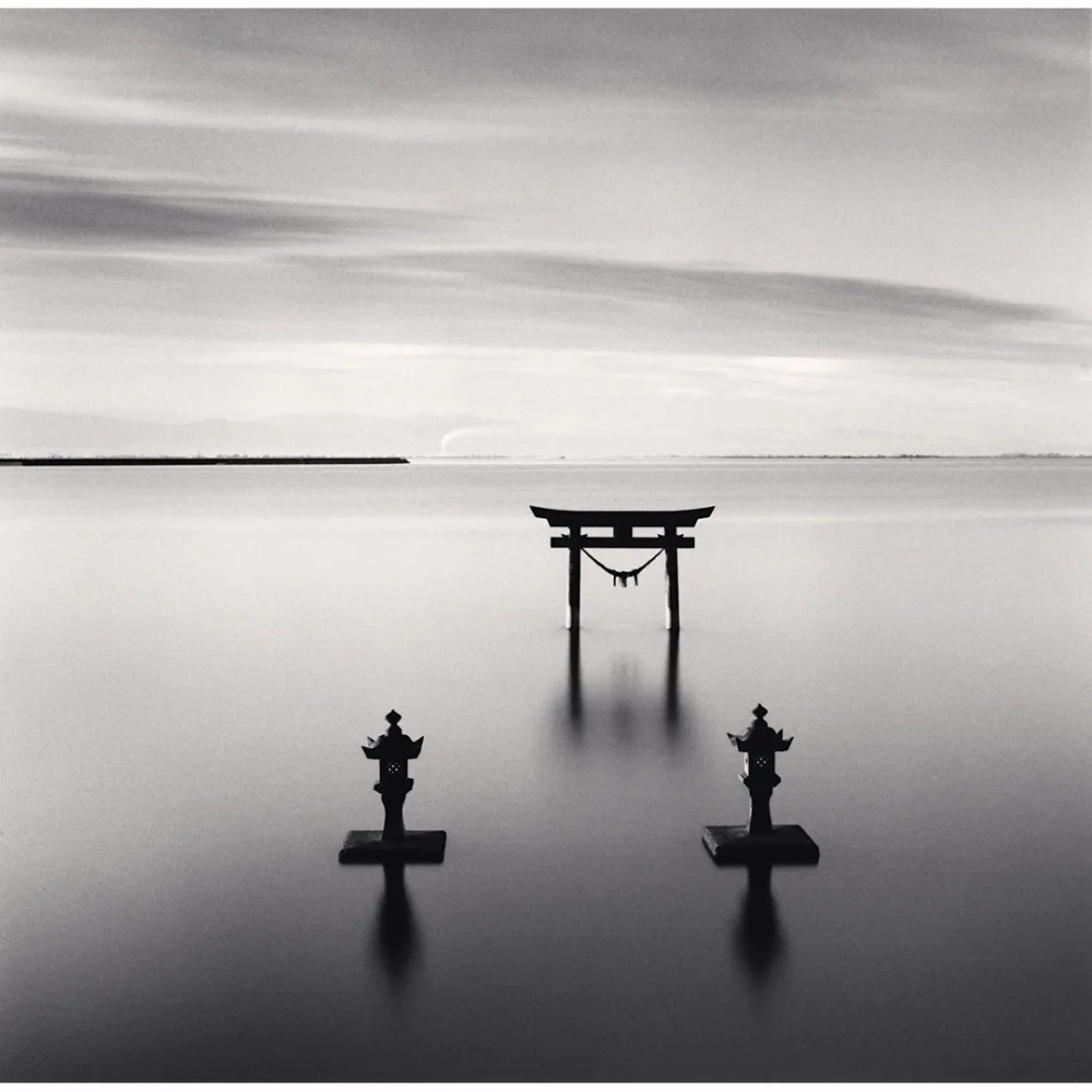 Torii et lanternes shinto émergeant de l’eau au large de Kyushu, photographiés en longue pose par Michael Kenna en 2024.