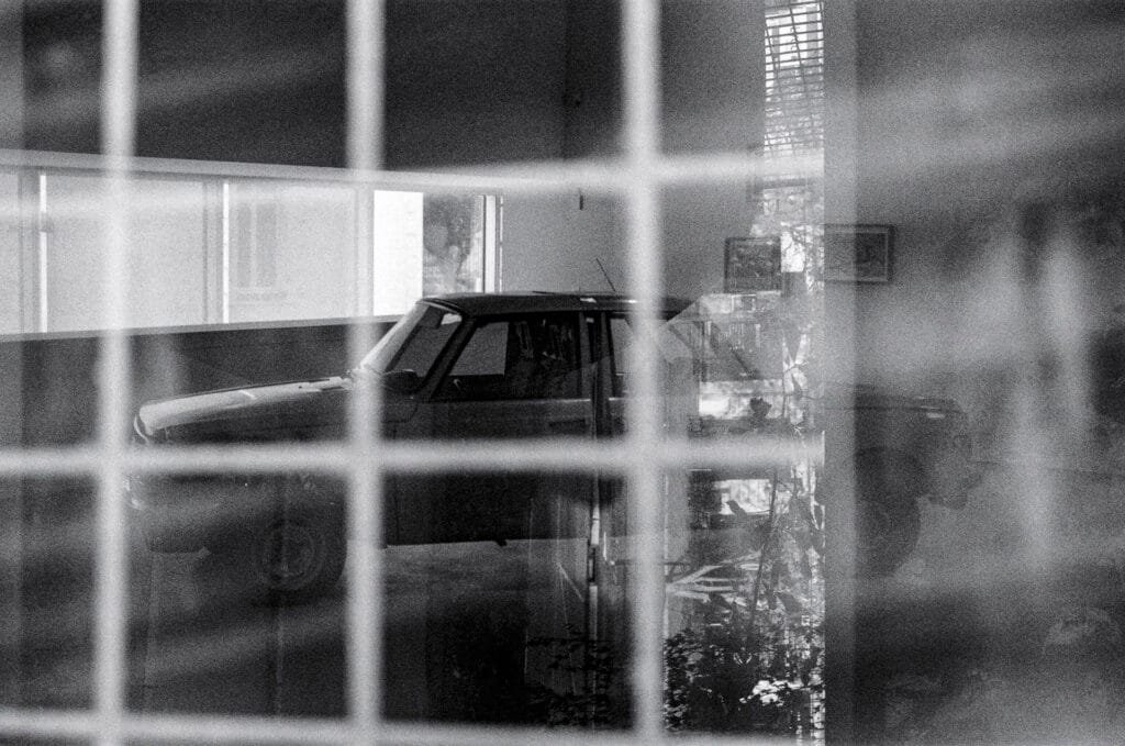 Superposition accidentelle entre l’œuvre Voiture à double tranchant de Fabrice Hyber au Musée d’Art de Nantes et une scène du parking Gare Nord, en noir et blanc sur TMAX 400 périmée.