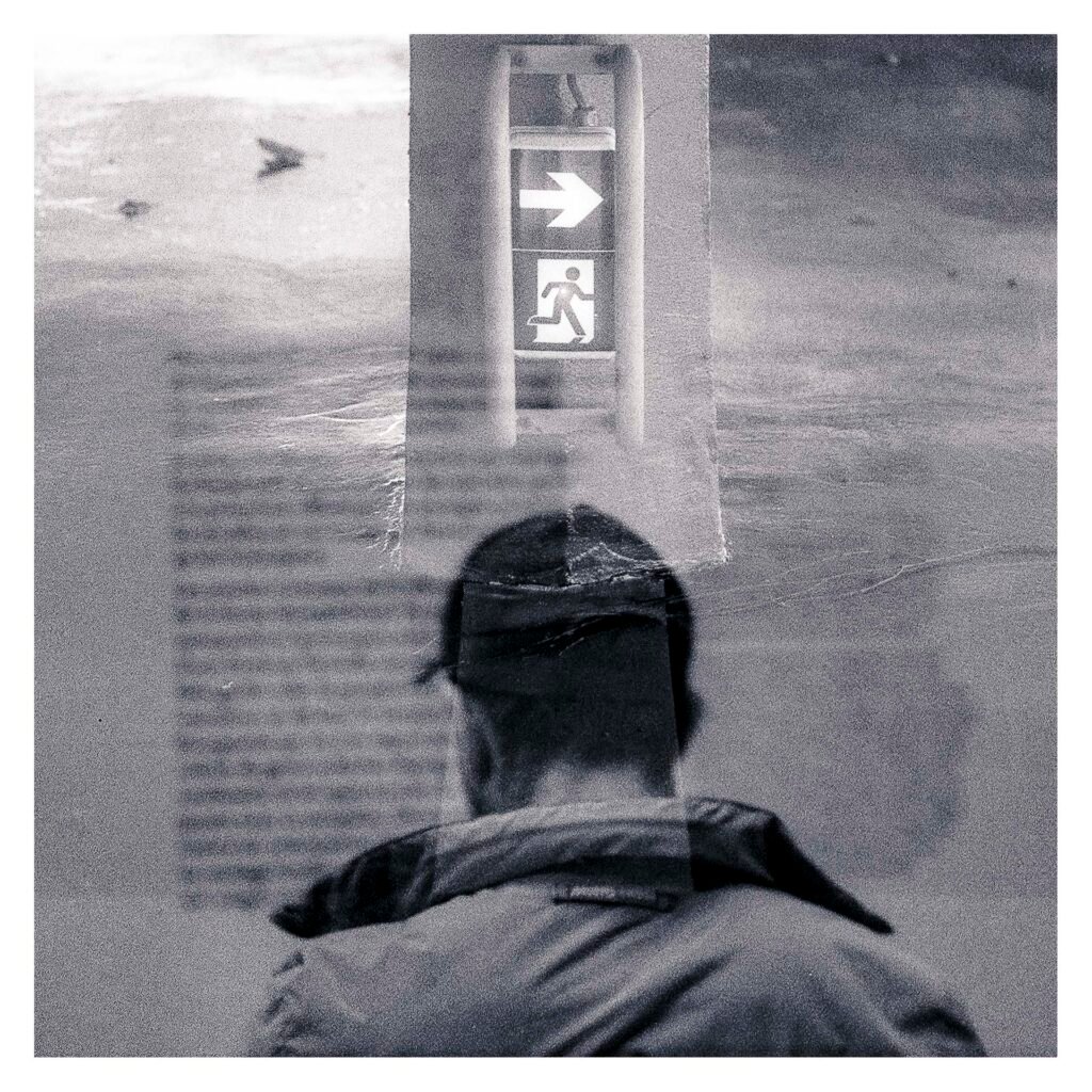 Silhouette superposée à un panneau lumineux de sortie de secours, en double exposition entre le Musée d’Art de Nantes et le parking Gare Nord.