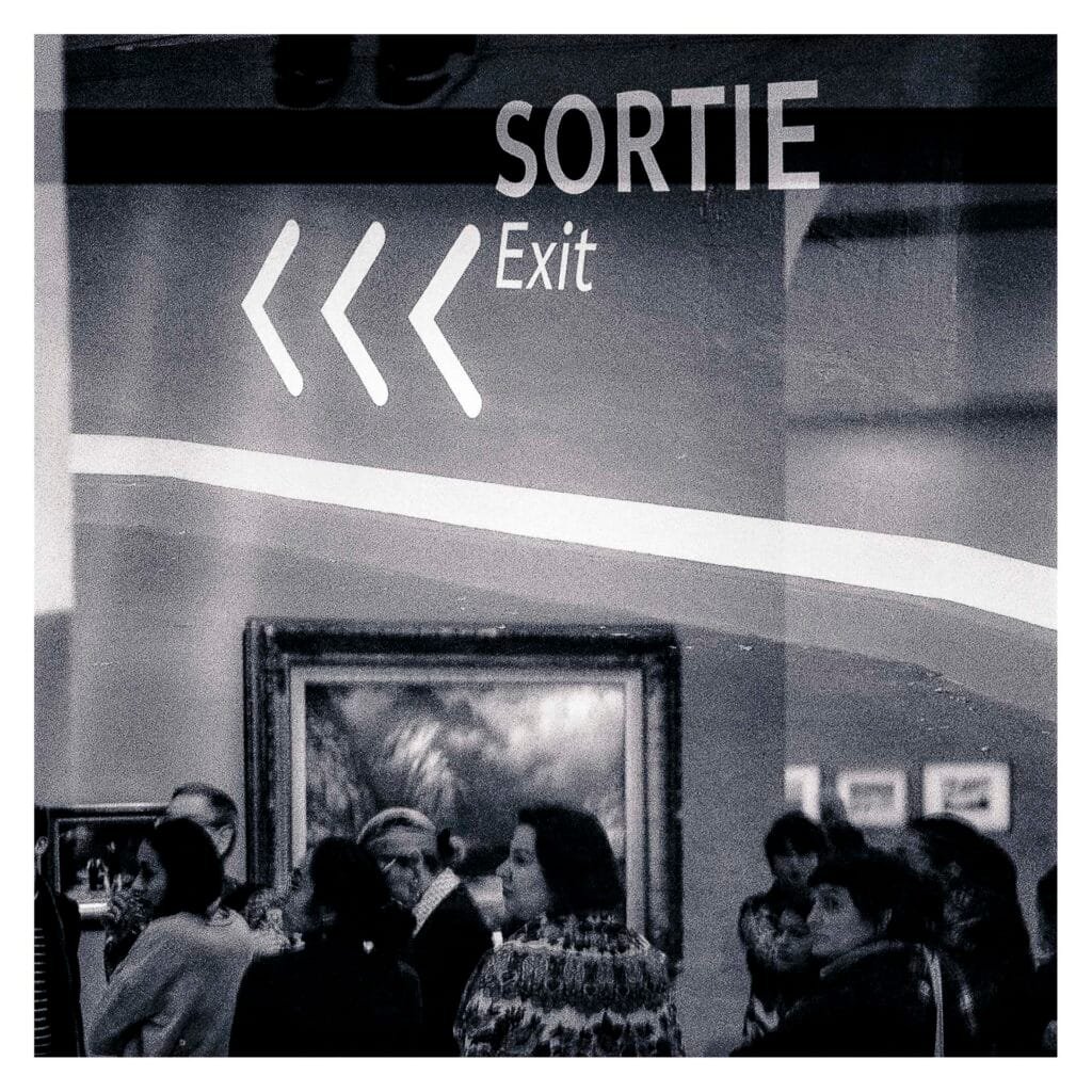 Foule dans une salle du Musée d’Art de Nantes, mêlée à une signalétique “Sortie” superposée en double exposition.