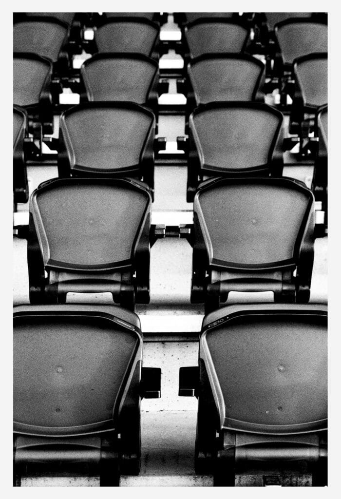 Rangées de sièges alignés dans les tribunes du stade nantais, photographiées en noir et blanc avec un rendu contrasté.