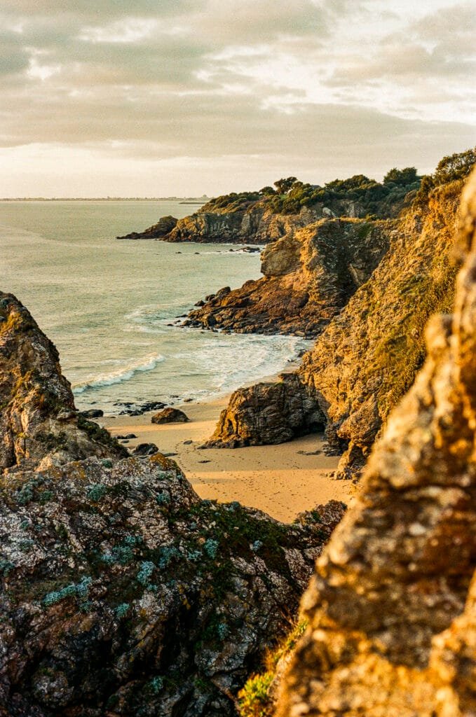 Petite crique entre les falaises de la côte, baignée par une lumière dorée en fin de journée d’hiver.