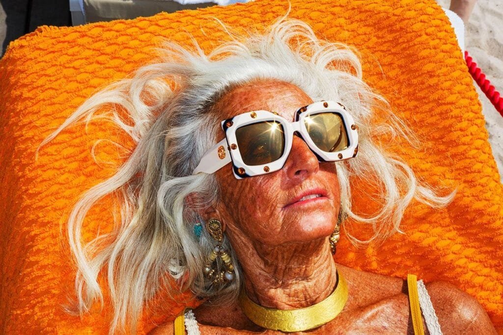 Femme allongée au soleil à Cannes portant de larges lunettes blanches décorées, photographiée par Martin Parr pour une commande Gucci en 2018.