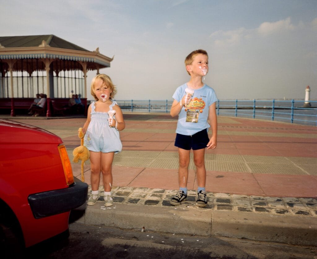 Enfants mangeant une glace sur la promenade de New Brighton, scène de bord de mer photographiée par Martin Parr dans la série The Last Resort.
