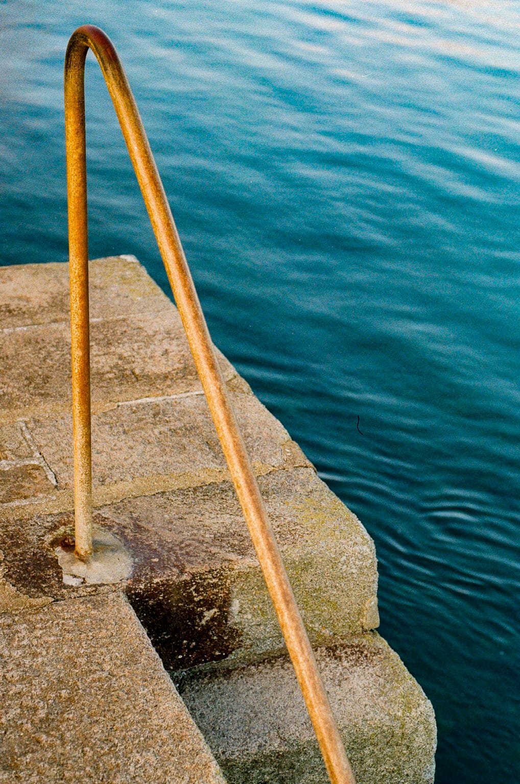 Rampe métallique rouillée sur la jetée du phare du Croisic, surplombant une mer calme. Photo en couleur au Nikon F3 HP.