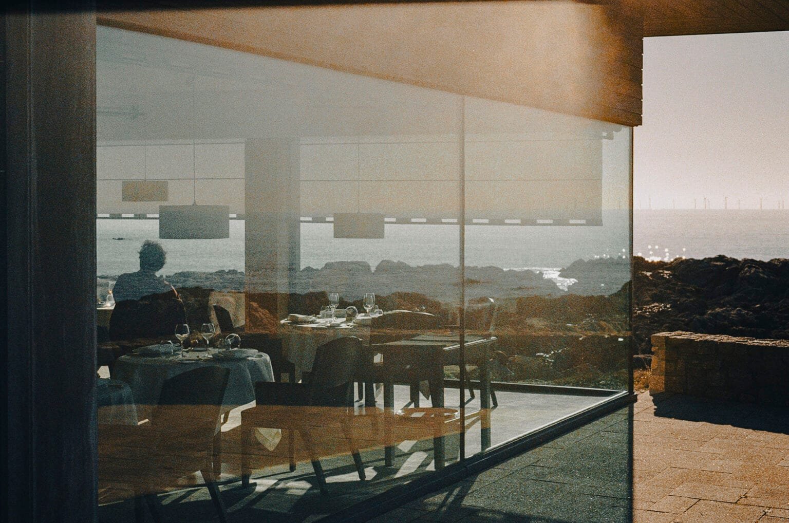 Reflets d’un restaurant face à la mer au Croisic, silhouette de client et tables dressées en contre-jour à travers les vitres.