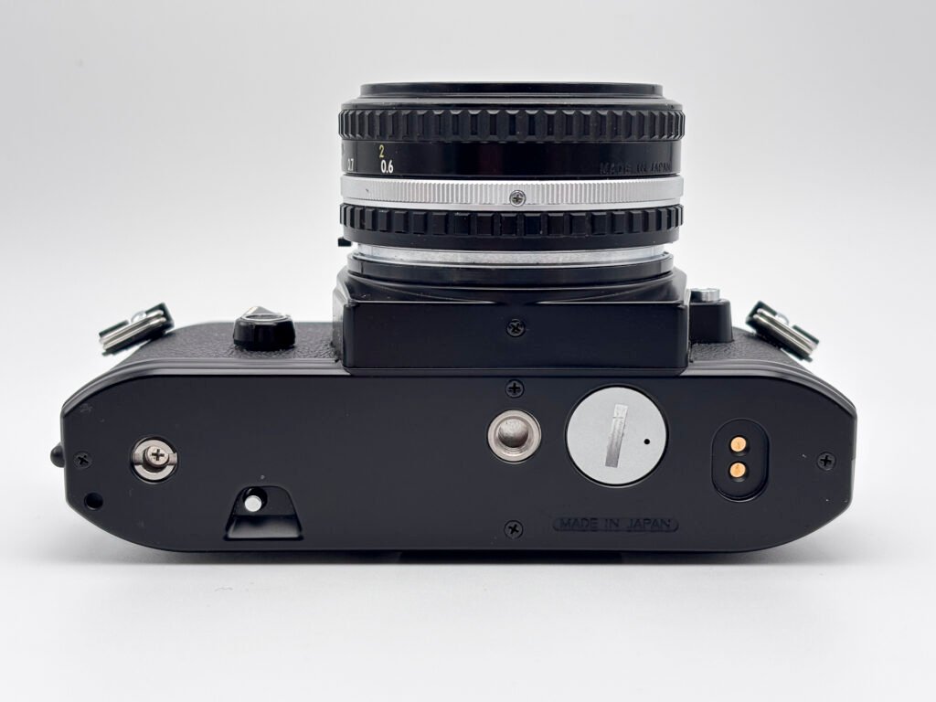 Dessous du Nikon EM montrant la trappe piles et la gravure Made in Japan.