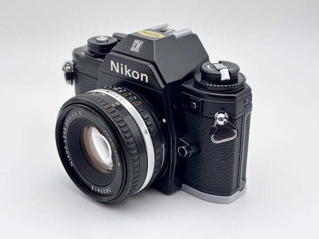 Nikon EM avec objectif Series E 50mm f/1.8 vu en trois quarts, reflex argentique compact lancé en 1979.