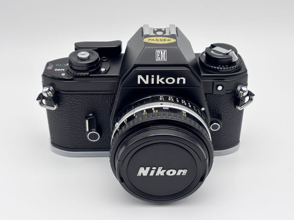 Nikon EM vu de face avec objectif Series E 50mm f/1.8 monté et bouchon Nikon.