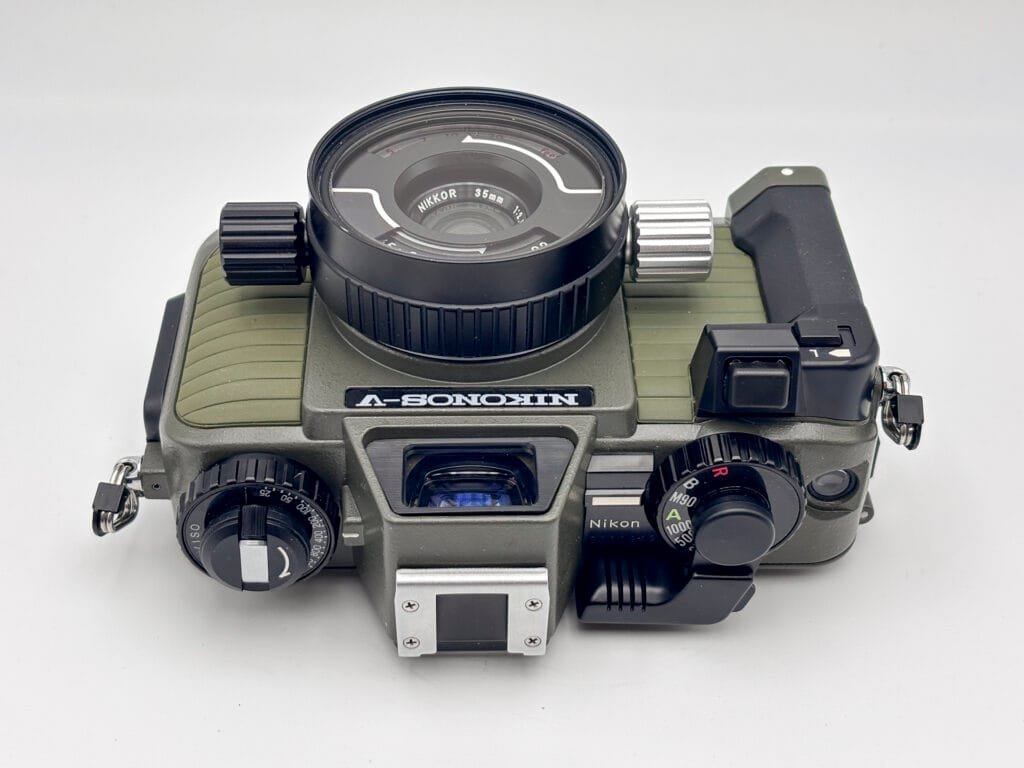 Vue du dessus du Nikonos V avec objectif Nikkor 35 mm, montrant le levier d’armement, les molettes de réglage et le viseur.
