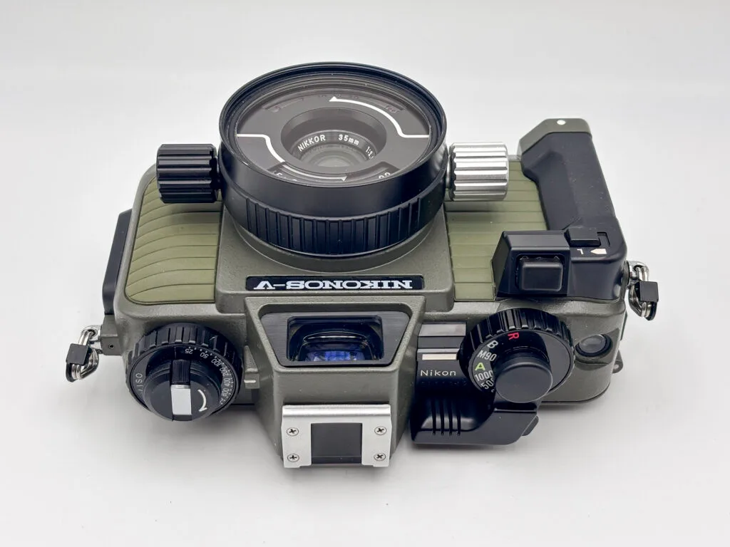 Vue du dessus du Nikonos V avec objectif Nikkor 35 mm, montrant le levier d’armement, les molettes de réglage et le viseur.