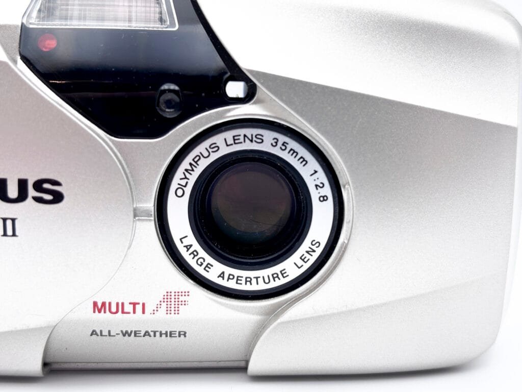 Gros plan de l’objectif Olympus Lens 35mm f/2.8 du compact Olympus Mju II.
