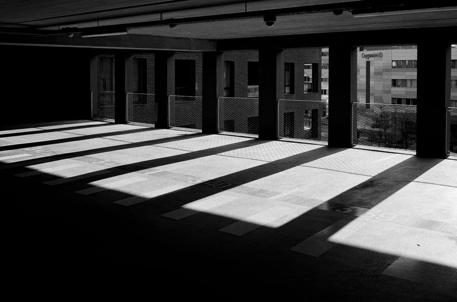 Intérieur du parking Gare Sud à Nantes, avec des lignes de béton, des piliers alignés et de fortes ombres projetées par la lumière naturelle.