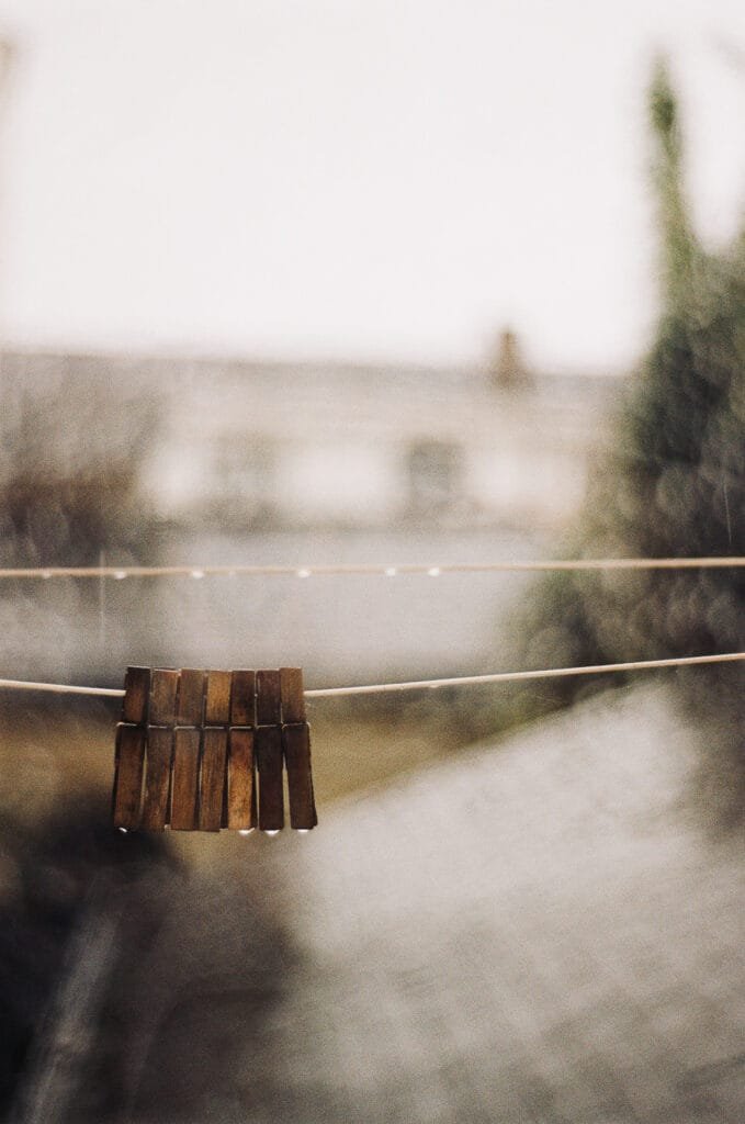 Pinces à linge en bois suspendues sur un fil avec des gouttes de pluie, arrière-plan flou.