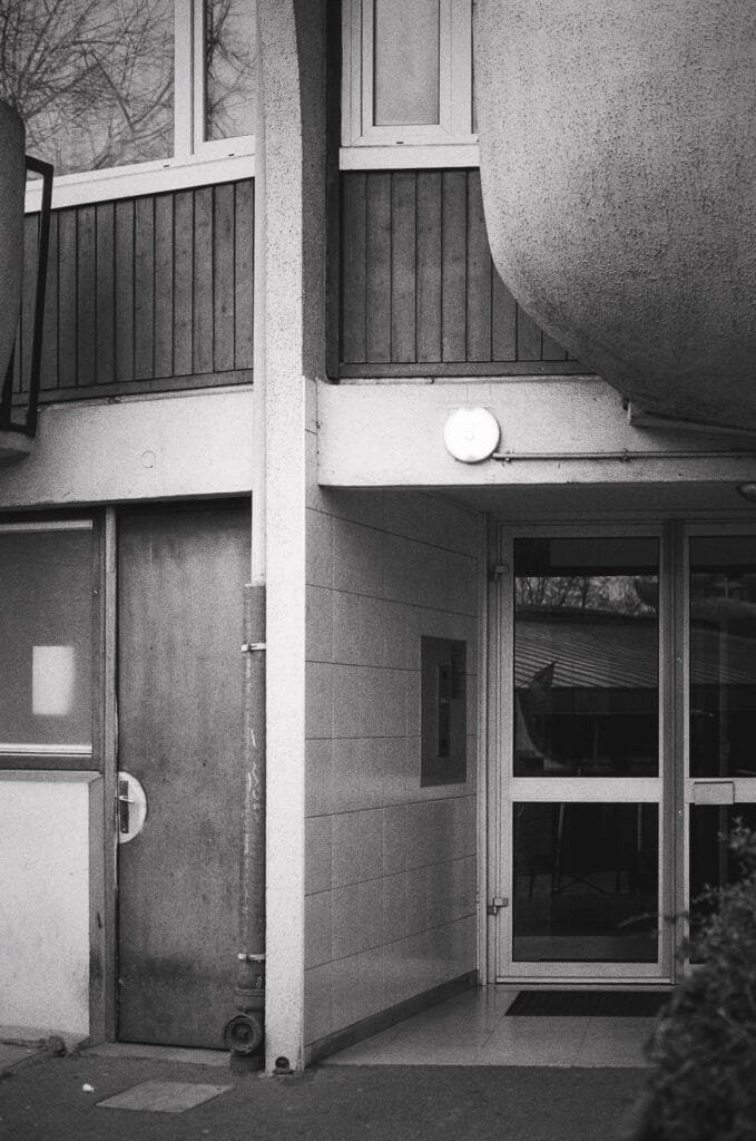 Entrée d’une tour des Choux de Créteil avec balcon arrondi au-dessus