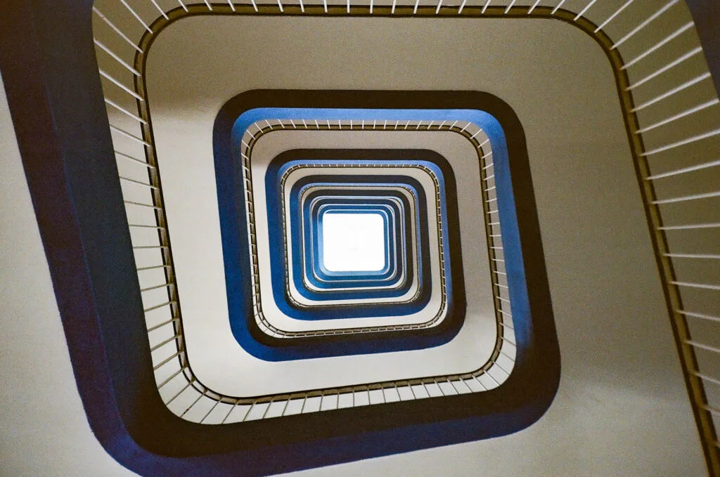 Vue en contre-plongée d’un escalier en colimaçon au CHU de Nantes avec formes géométriques répétées