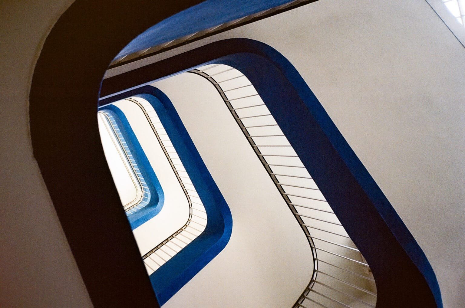 Vue en contre-plongée d’un escalier au CHU de Nantes avec lignes courbes et teintes bleues