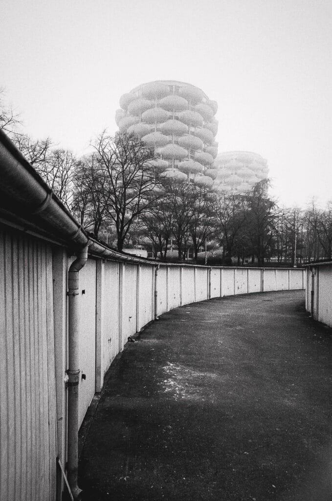 Allée courbe de garages au pied des tours des Choux de Créteil dans une ambiance brumeuse