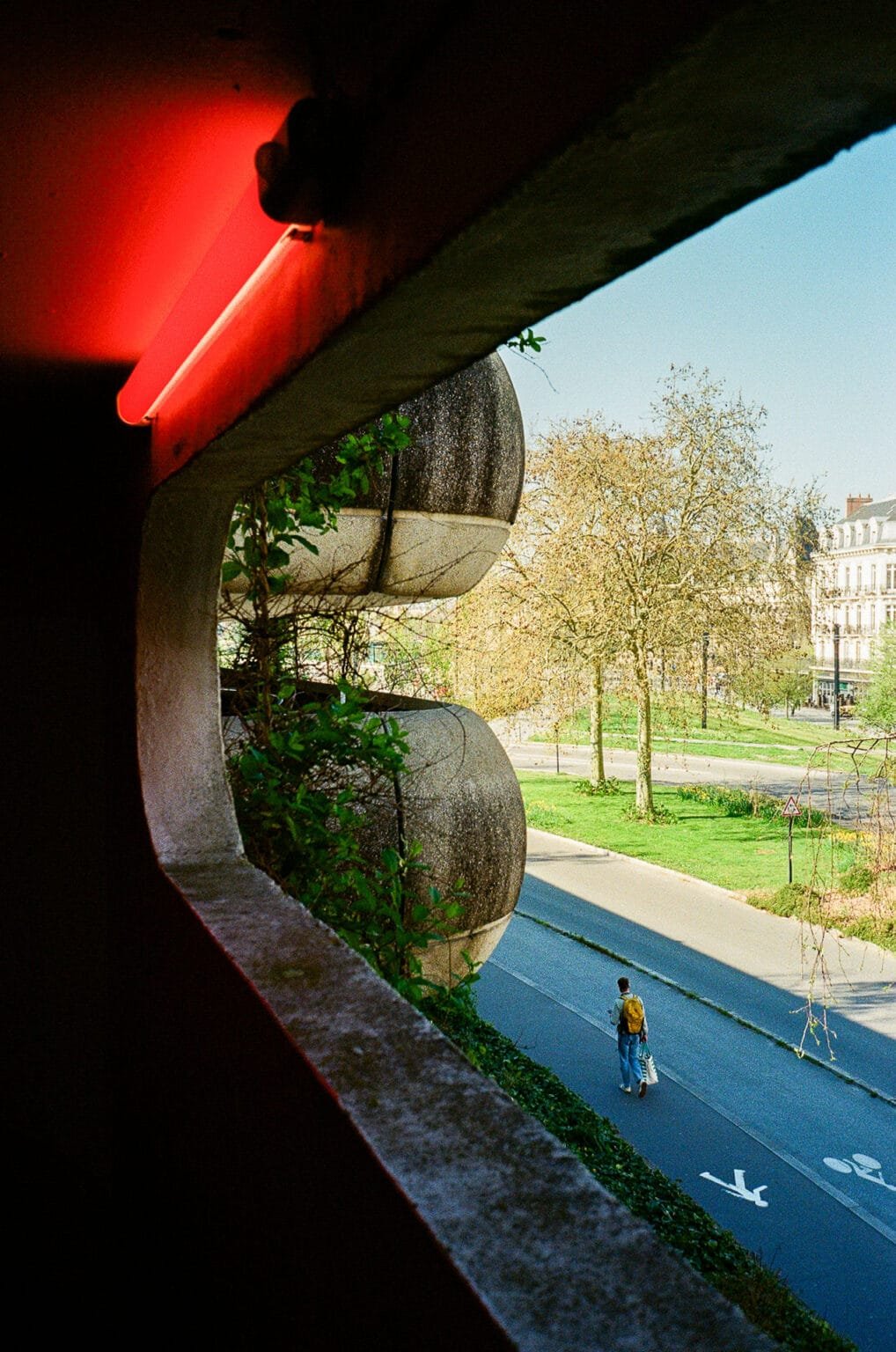Vue depuis un parking à Nantes avec un éclairage rouge au premier plan et un passant dans la rue en contrebas