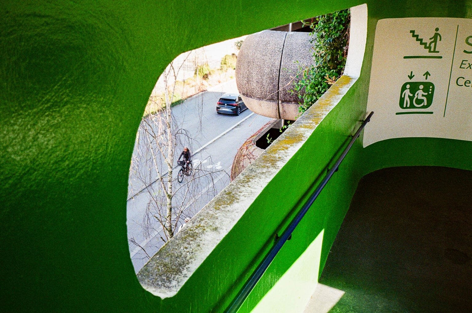 Vue depuis un parking à Nantes avec encadrement vert et un cycliste passant dans la rue en contrebas