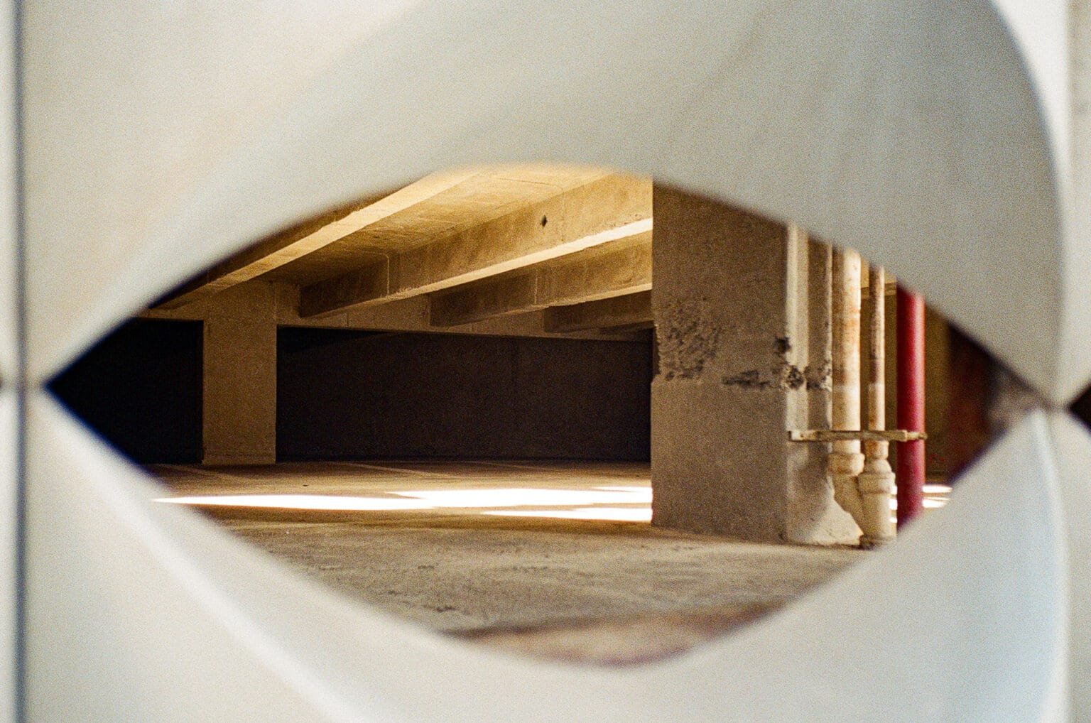 Vue d’un parking à Nantes cadrée à travers une ouverture, avec jeux de lumière et structures en béton