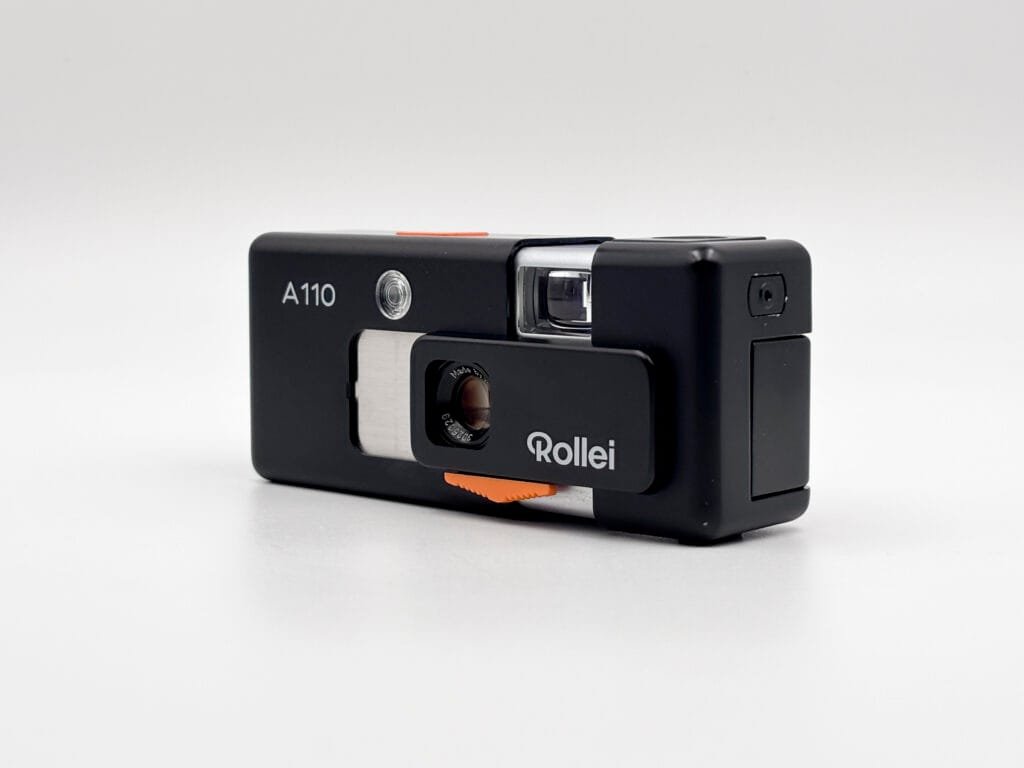 Rollei A110 ouvert en vue de trois quarts avec objectif Tessar visible et prise pour extension flash sur le côté