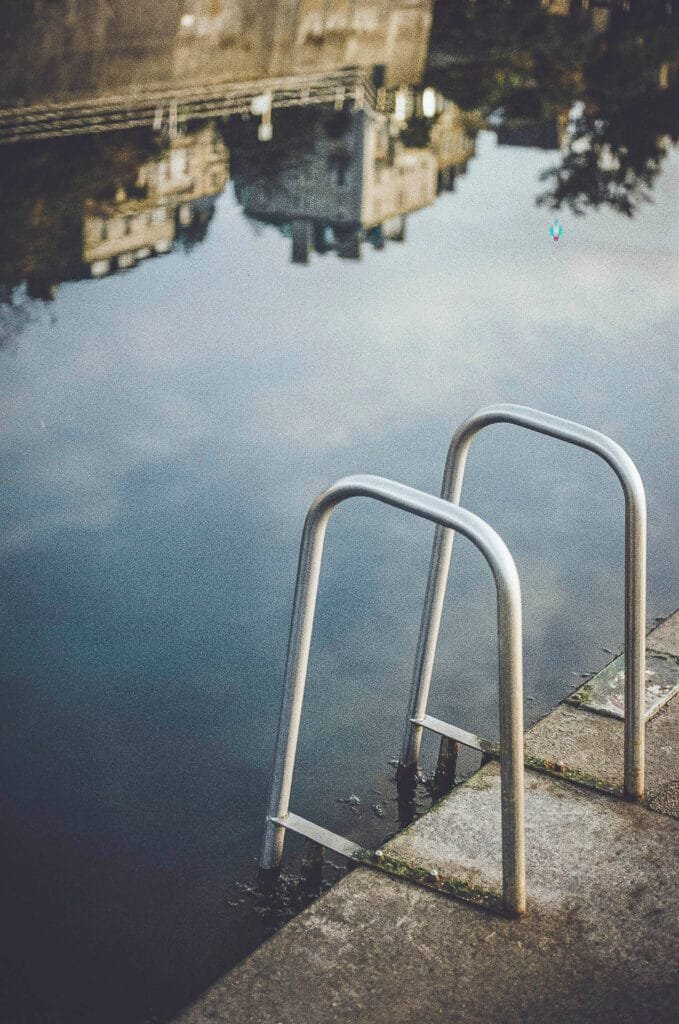 Vue en plongée sur une échelle de la piscine du Prieuré à Dinard, reflets des bâtiments dans l'eau, photo argentique Nikon F3