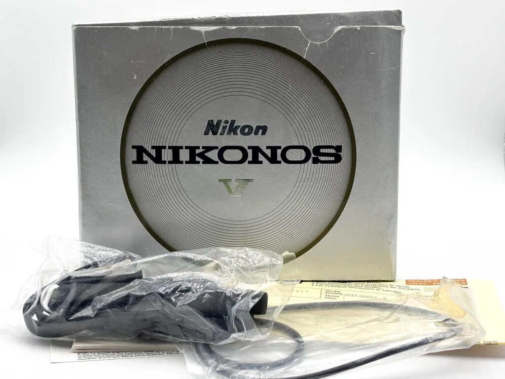 Boîte d'origine du Nikonos V orange avec documents, carte de garantie Nikon France et accessoires d'origine sous plastique