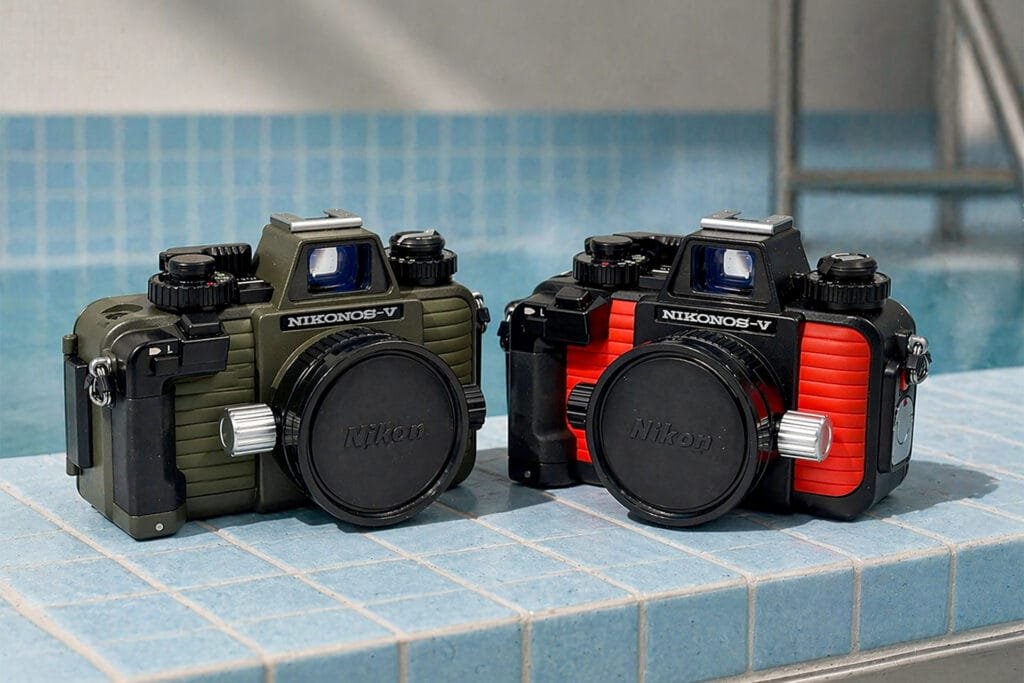 Deux boîtiers Nikonos V côte à côte, version kaki à gauche et version orange à droite, sans objectif sur fond blanc