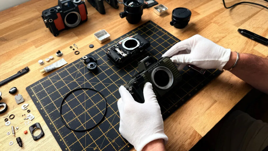 Démontage du Nikonos V vert olive dans l'atelier de YannB, gants blancs, pièces et joints étalés sur tapis de découpe - © YannB / yannb.net
